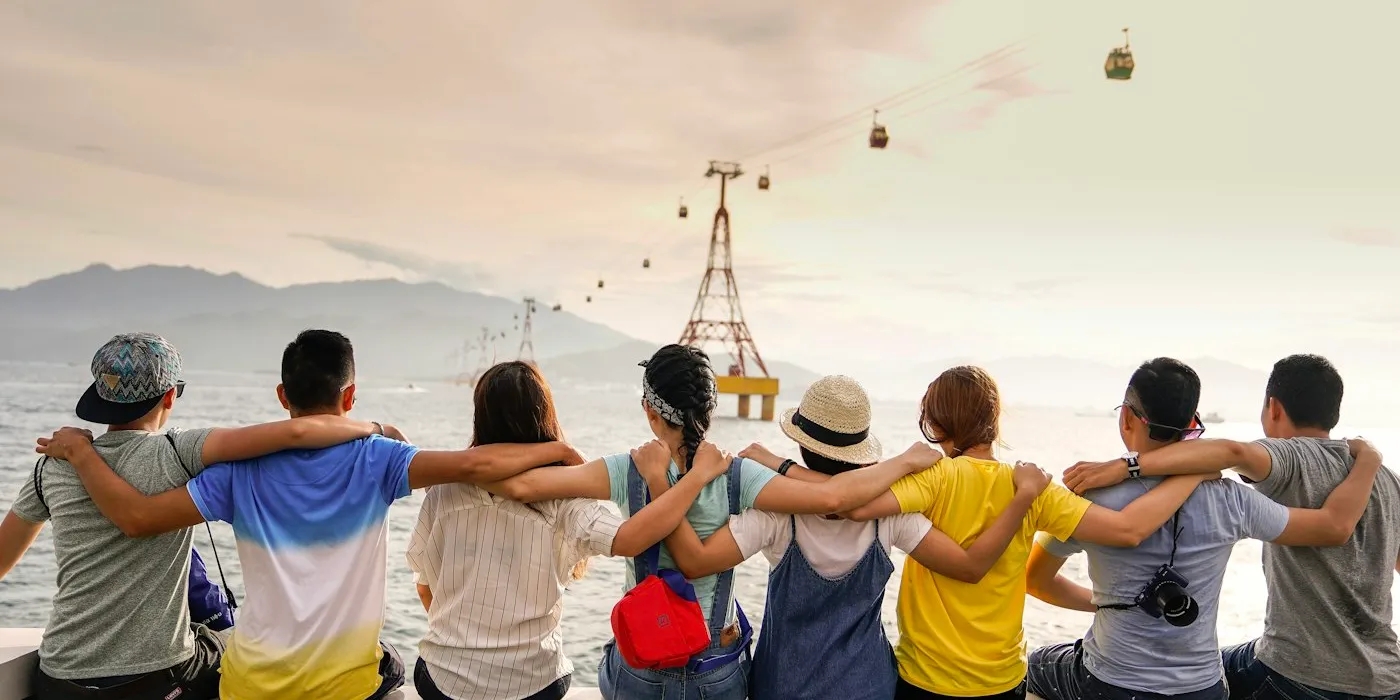 Friends sitting side by side with their arms around each other's shoulders