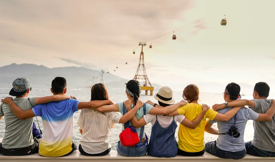 Friends sitting side by side with their arms around each other's shoulders